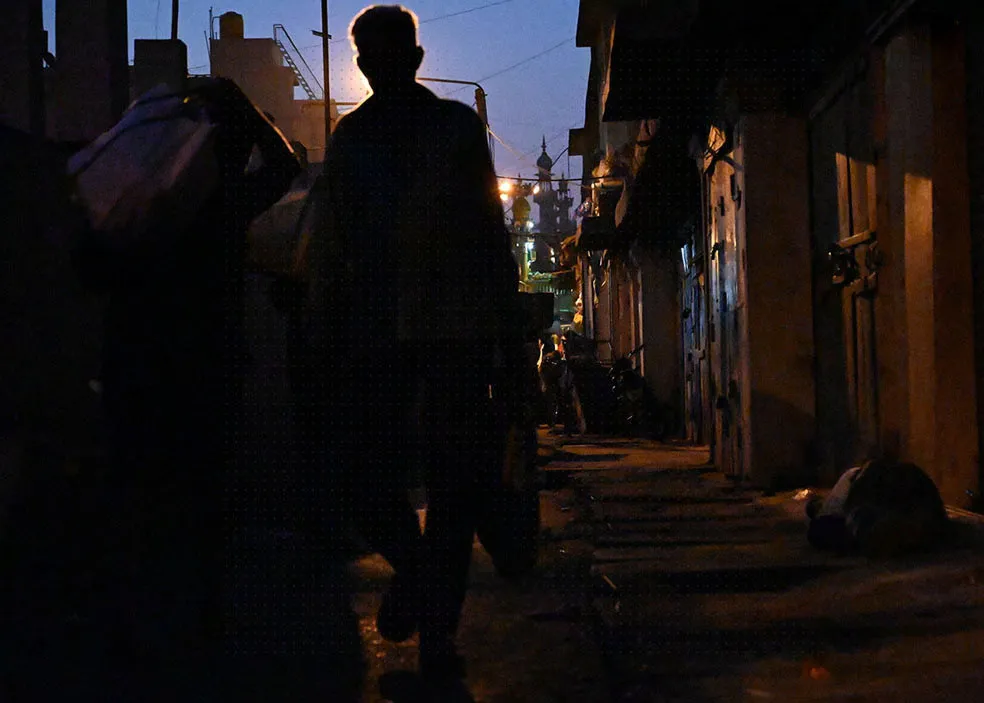 A father and his two sons are hurrying along, carrying vegetable bags at Chickpete Market